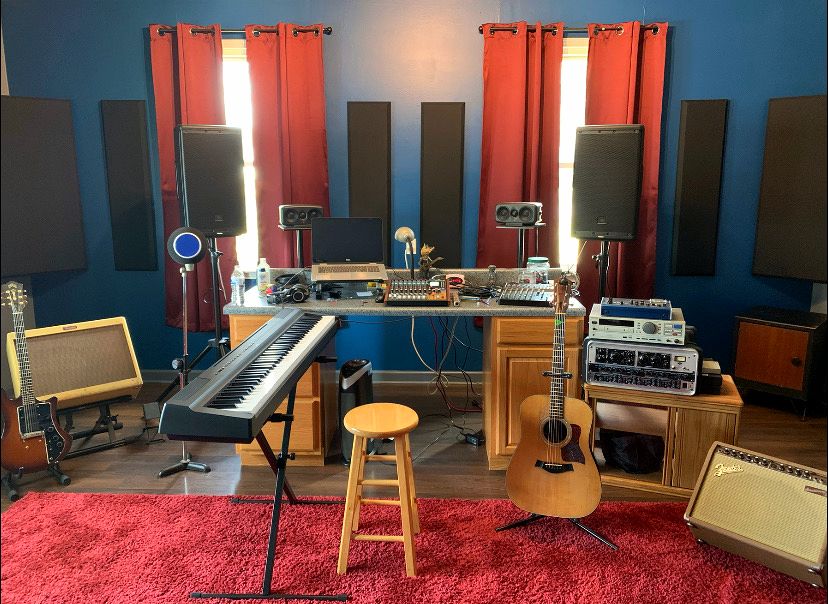 Studio with keyboard, acoustic guitar, monitors and a red rug