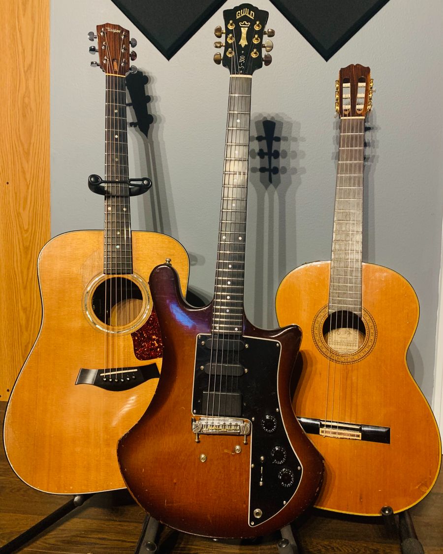 Two acoustic guitars and an electric guitar standing side by side