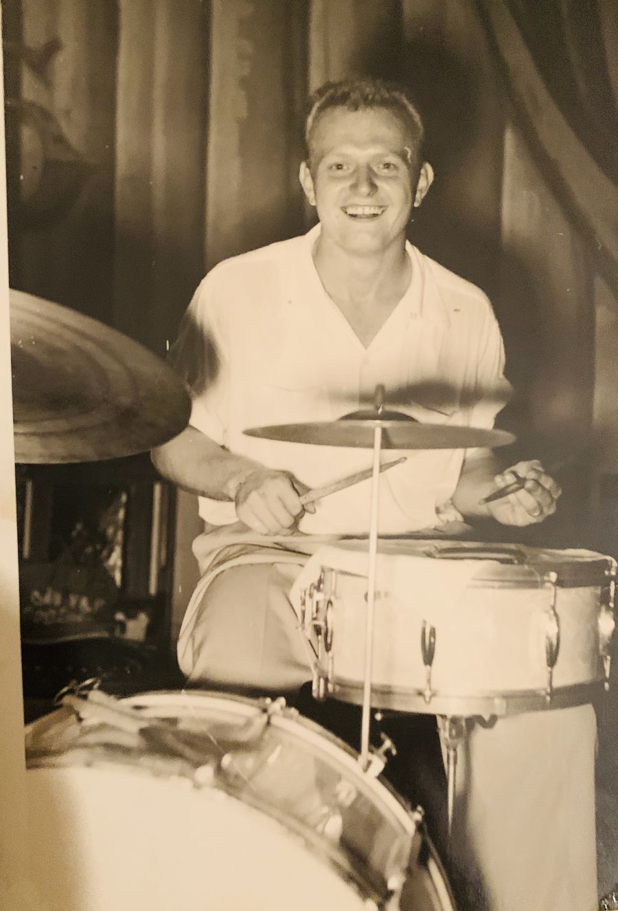 Black-and-white photo of Edwin “Whitey” Pawola smiling behind a drum kit